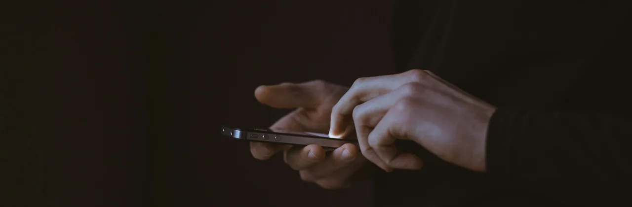 Manos usando un teléfono en penumbra
