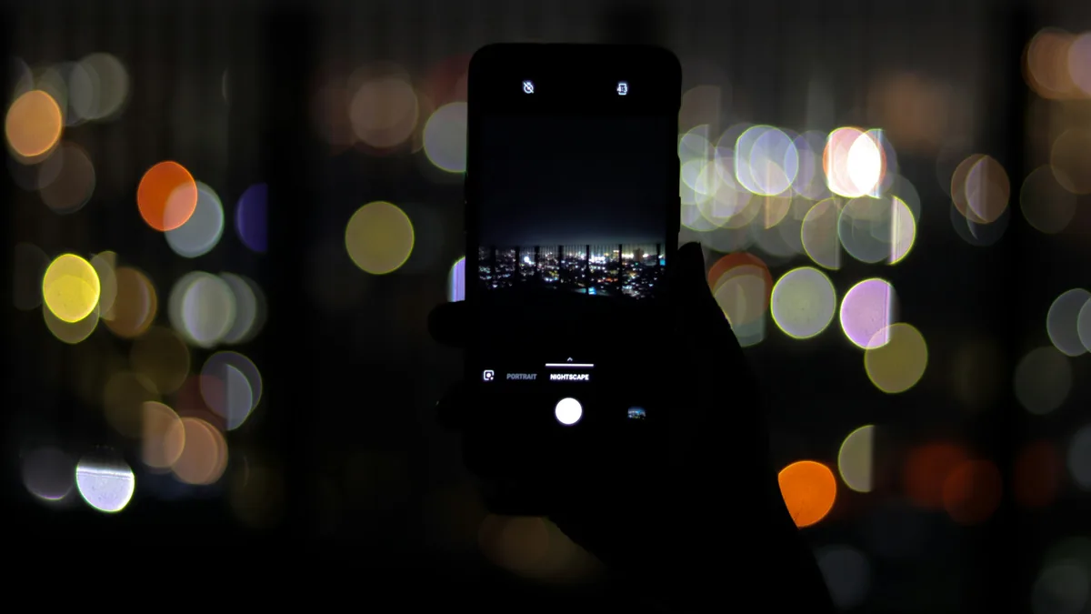 Teléfono sostenido de noche contra luces desenfocadas