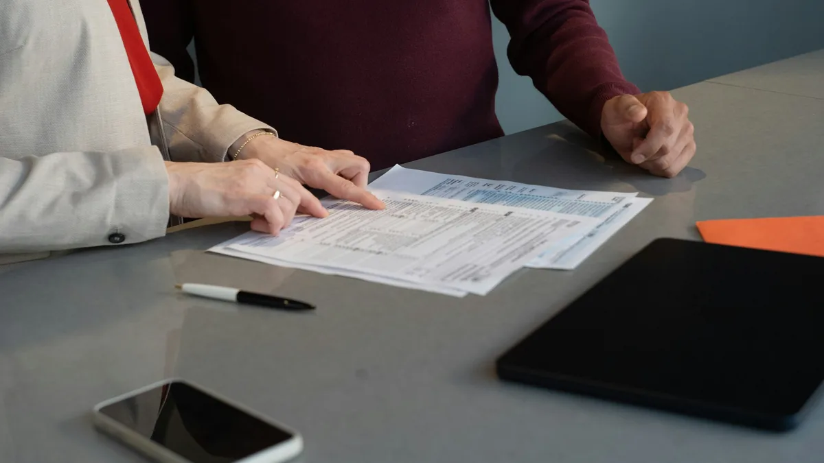 Dos personas revisando un formulario en papel sobre una mesa