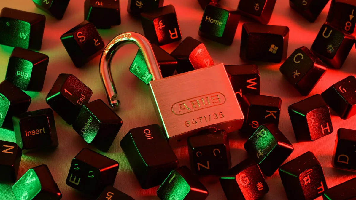 Candado abierto entre teclas de teclado sueltas, con luz roja y verde